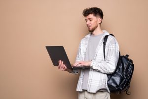 young male student with modern laptop color background scaled 1